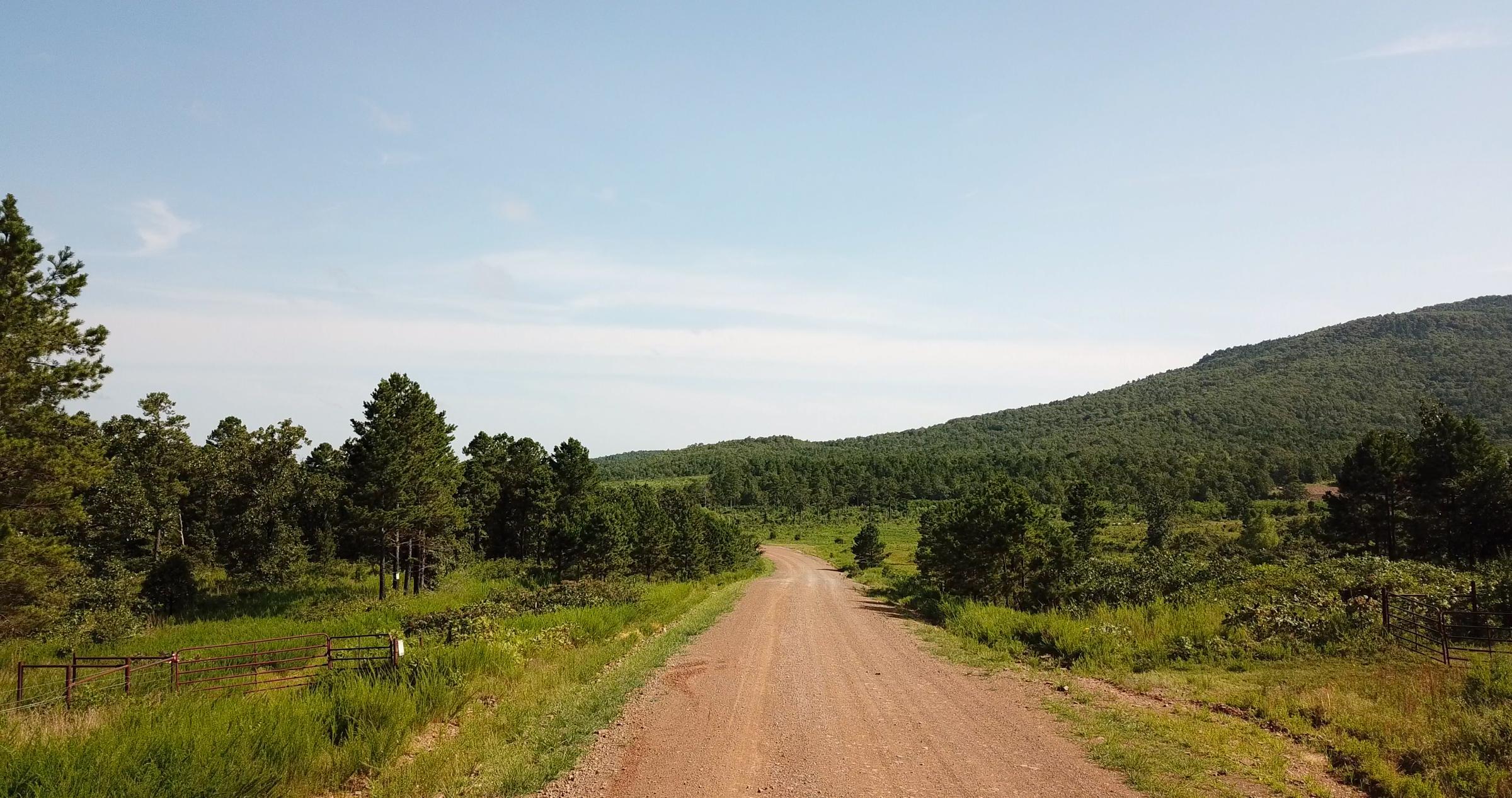A gravel road running toward a forested ridge of the Ouachita Mountains in LeFlore County, Oklahoma